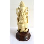 DETAILED IVORY CARVING OF GANESHA raised on a circular mahogany plinth, 16.5cm high