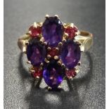 UNUSUAL AMETHYST AND RUBY CLUSTER RING the four oval cut amethysts interspersed with small rubies,