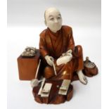 CARVED JAPANESE IVORY AND BOXWOOD OKIMINO of a Noh mask maker, seated with his masks and tools