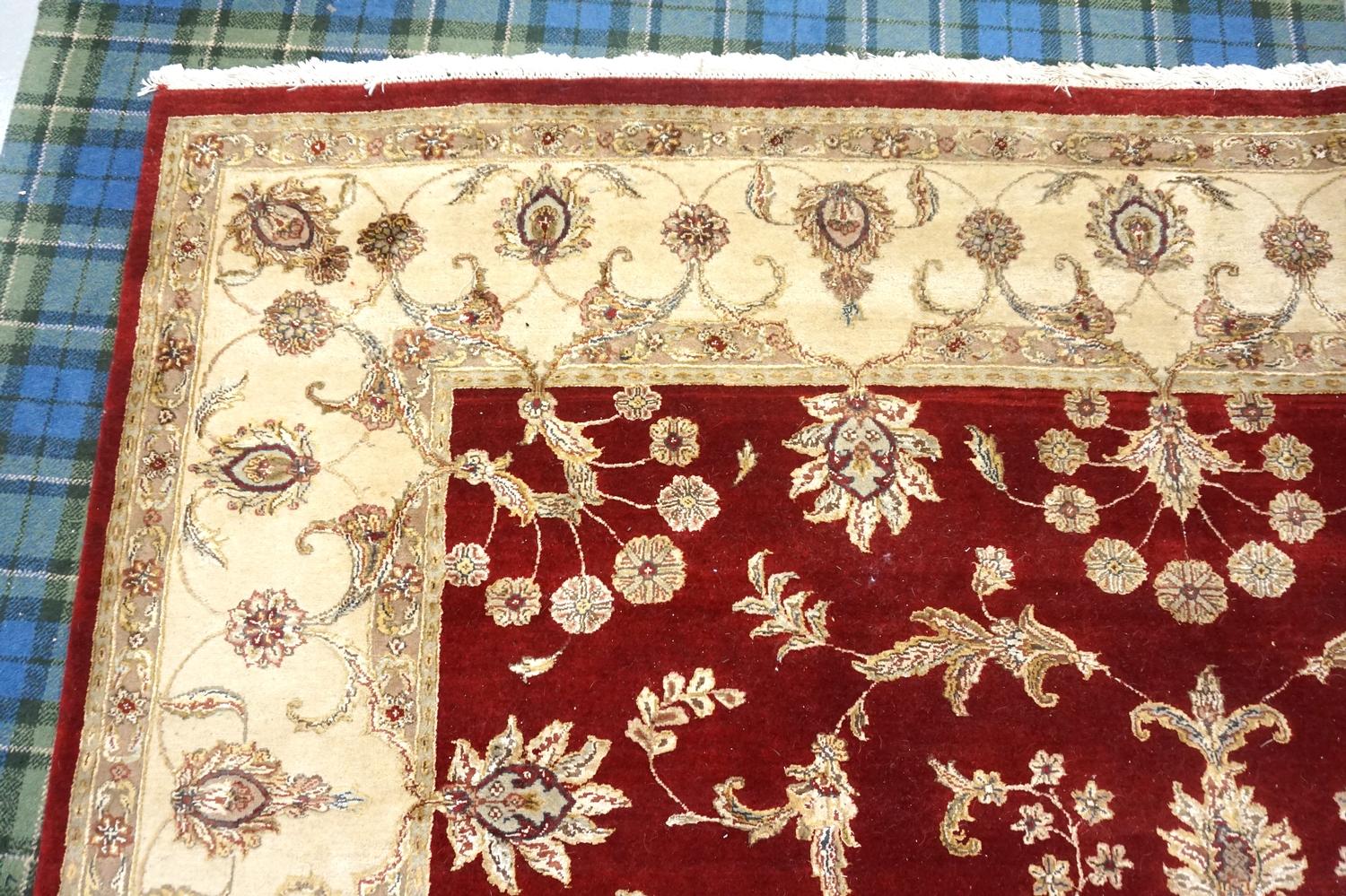 LARGE EASTERN FLOOR RUG with a claret ground decorated with floral motifs encased by a taupe border,