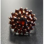 GARNET CLUSTER DRESS RING the central garnet in double garnet surround, on nine carat rose gold