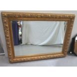 LARGE OBLONG GILT FRAME MIRROR decorated with flower heads around a bevelled plate, 81.5cm x 112cm