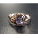 AMETHYST SINGLE STONE RING the oval cut amethyst flanked by pierced scroll decorated shoulders, on