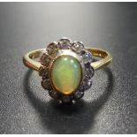 OPAL AND DIAMOND CLUSTER RING the central opal in twelve diamond surround, on eighteen carat gold