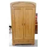 WAXED PINE WARDROBE the arched top above a pair of panelled doors opening to reveal a shelf and