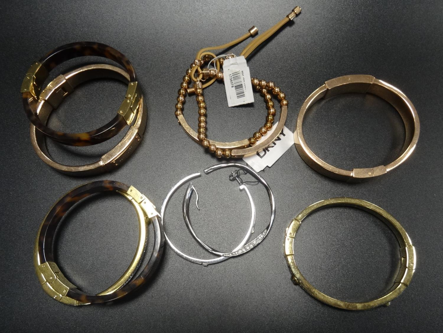 EIGHT MICHAEL KORS BRACELETS comprising two pave crystal set yellow gold tone bangles, two logo