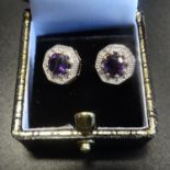 PAIR OF AMETHYST AND DIAMOND EARRINGS the central round cut amethyst on each within textured