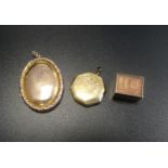 NINE CARAT GOLD CASED BANKNOTE CHARM together with two rolled gold locket pendants, one oval and one