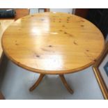 WAXED PINE KITCHEN TABLE with a circular top on a turned column with four outswept supports, 102cm