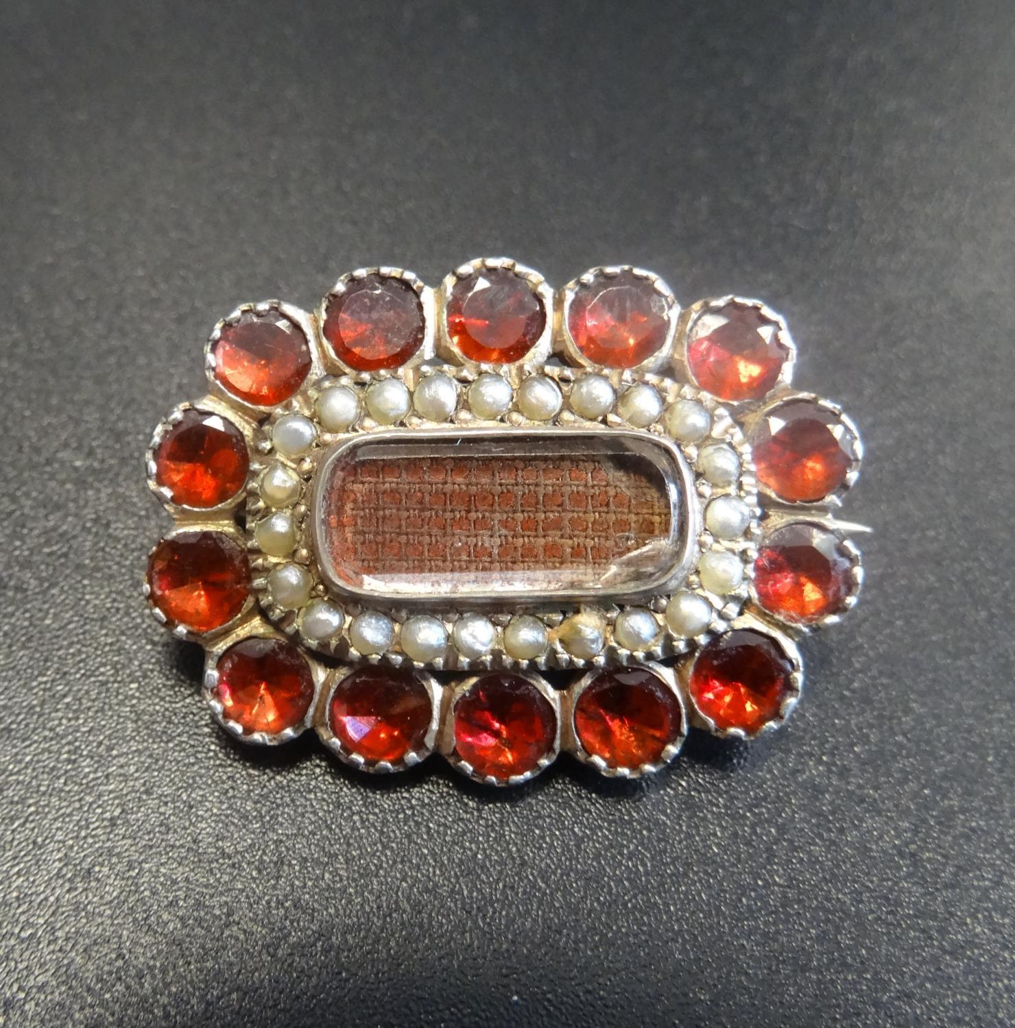 GEORGIAN BROOCH the central glazed panel containing woven hair, in surround of seed pearls and