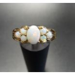 OPAL CLUSTER RING the central oval cabochon opal flanked by three round cabochon opals to each side,