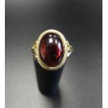 GARNET DRESS RING the large oval cabochon garnet in rope twist effect mount, on nine carat gold