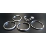 FIVE SILVER BANGLES of various size and design, including a wavy example and another with engraved