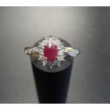 RUBY AND DIAMOND CLUSTER RING the central oval cut ruby in twelve diamond surround and with