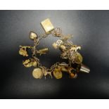 NINE CARAT GOLD CHARM BRACELET with a good selection of charms including an egg opening to reveal