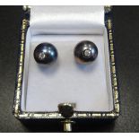 UNUSUAL PAIR OF BLACK PEARL AND DIAMOND STUD EARRINGS the diamond set posts to the centre of each