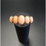 GRADUATED CORAL FIVE STONE RING on nine carat gold shank with decorative shoulders, ring size N