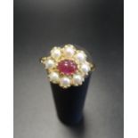 RUBY AND PEARL CLUSTER DRESS RING the central oval cabochon ruby in eight diamond surround, on
