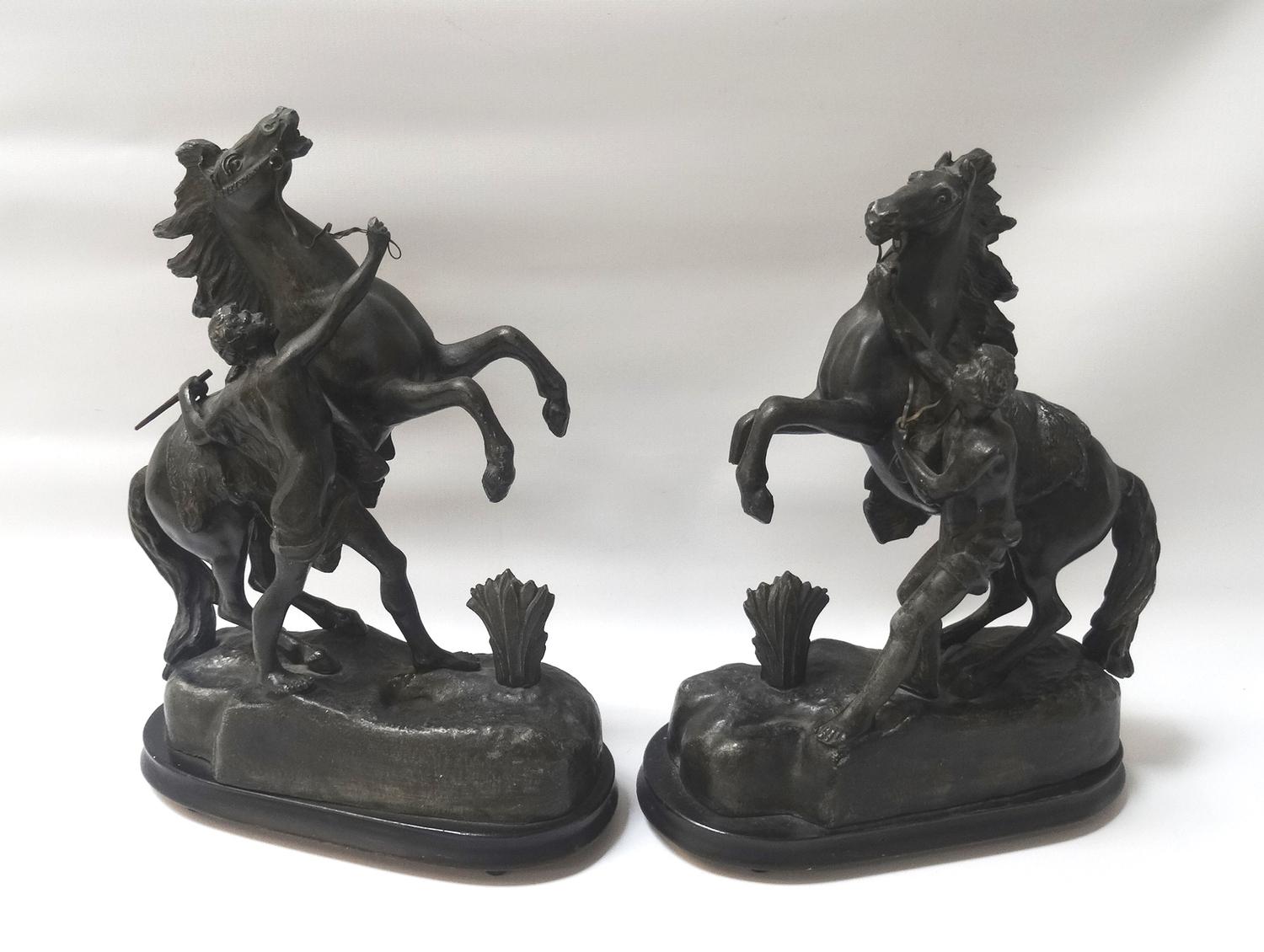 PAIR OF SPELTER FIGURES each depicting a groom with a rearing horse on a naturalistic base, raised