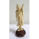 CHINESE CARVED IVORY FIGURE of an old man resting on his staff with his leg raised, 13cm high, on