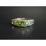 GRADUATED PERIDOT FIVE STONE RING on fifteen carat gold shank with silver setting, ring size M-N