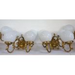 SET OF FOUR GILT BRASS WALL LIGHTS each with a pair of scroll arms and opaque circular glass shades