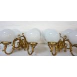 SET OF FOUR GILT BRASS WALL LIGHTS each with a pair of scroll arms and opaque circular glass shades