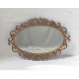 OVAL GILTWOOD WALL MIRROR decorated with scrolls, 82cm wide