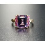 AMETHYST AND PINK GEM SET DRESS RING the central emerald cut amethyst flanked by a vertical row of