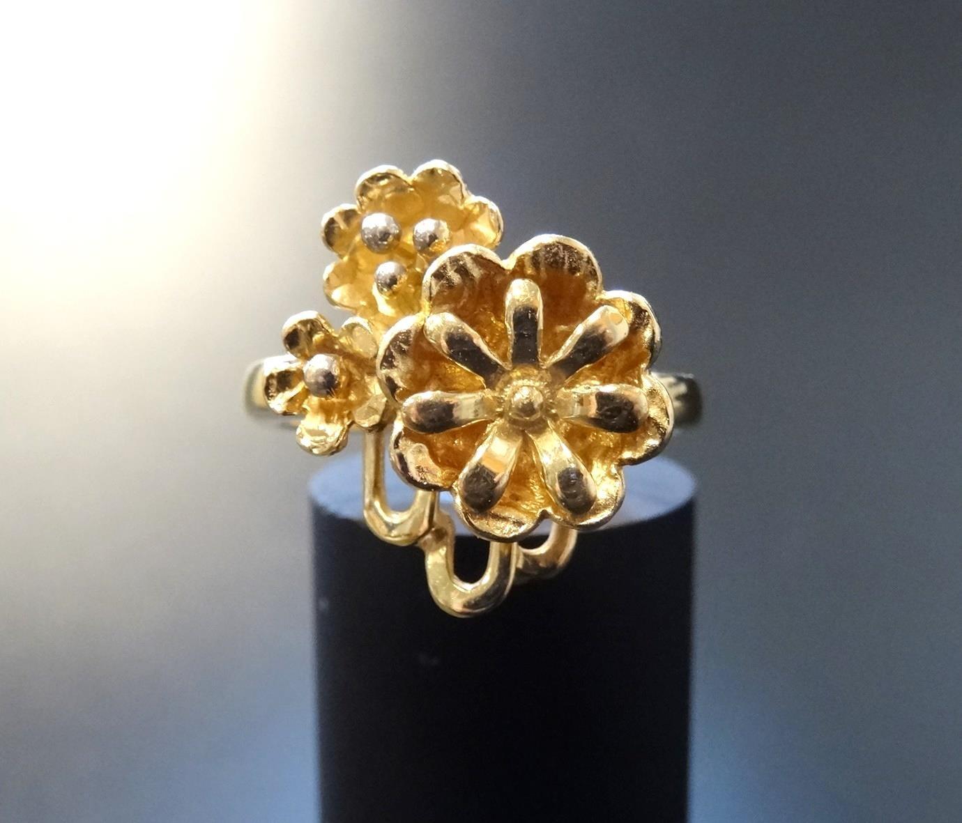 EIGHTEEN CARAT GOLD FLOWER DESIGN RING the larger flower head beside two smaller examples, ring size