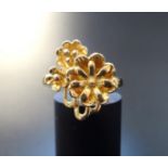 EIGHTEEN CARAT GOLD FLOWER DESIGN RING the larger flower head beside two smaller examples, ring size