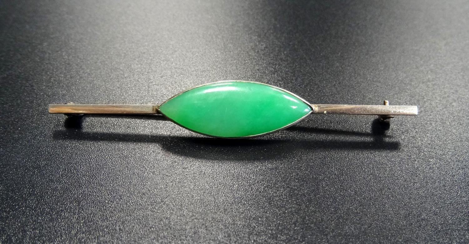 JADE SET BAR BROOCH the central navette shaped jade section on unmarked white gold bar, 7cm long