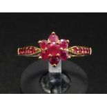 RUBY CLUSTER RING the central ruby in six ruby surround and with further rubies to the shoulders, on
