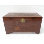 CHINESE CAMPHOR WOOD CHEST with a lift up lid carved with a village and fishing scene, with recessed