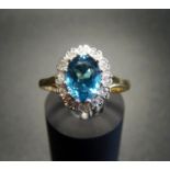 BLUE TOPAZ AND DIAMOND CLUSTER DRESS RING the central oval cut topaz in twelve diamond surround,