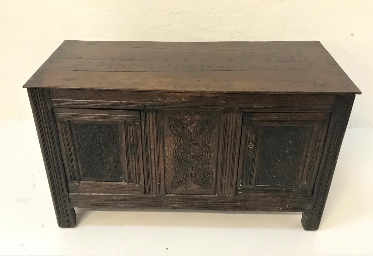 18TH CENTURY OAK COFFER with a plain top above a channel moulded frieze with a carved central