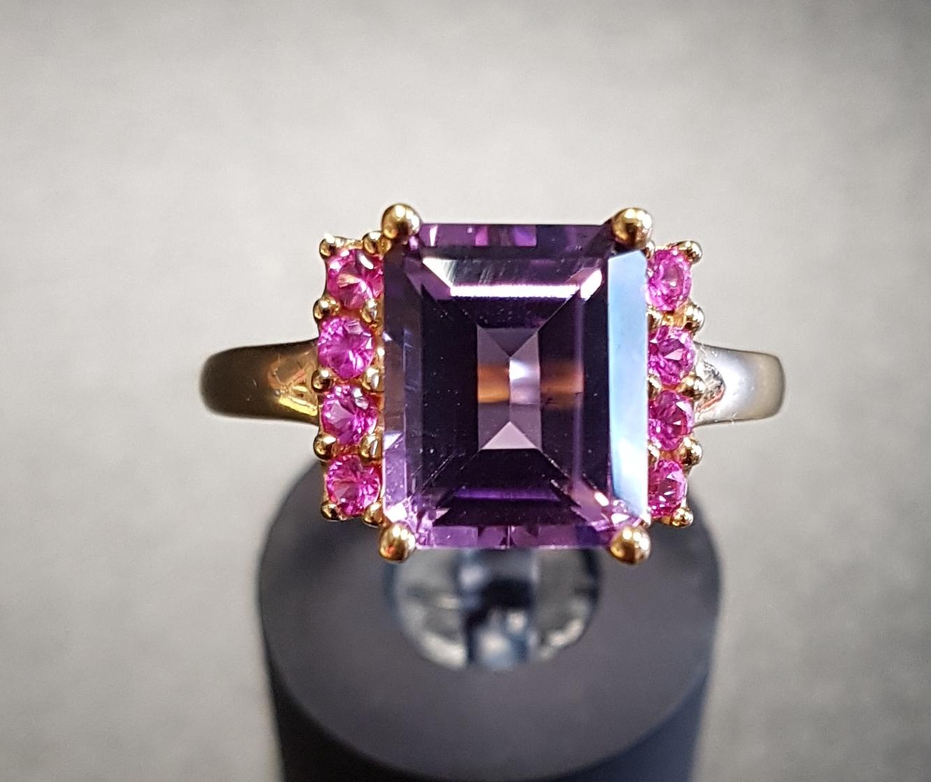 AMETHYST AND PINK GEM SET DRESS RING the central emerald cut amethyst flanked by a vertical row of