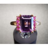 AMETHYST AND PINK GEM SET DRESS RING the central emerald cut amethyst flanked by a vertical row of