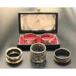 FIVE SILVER NAPKIN RINGS comprising a boxed pair by Walker and Hall, Birmingham 1960; a George V
