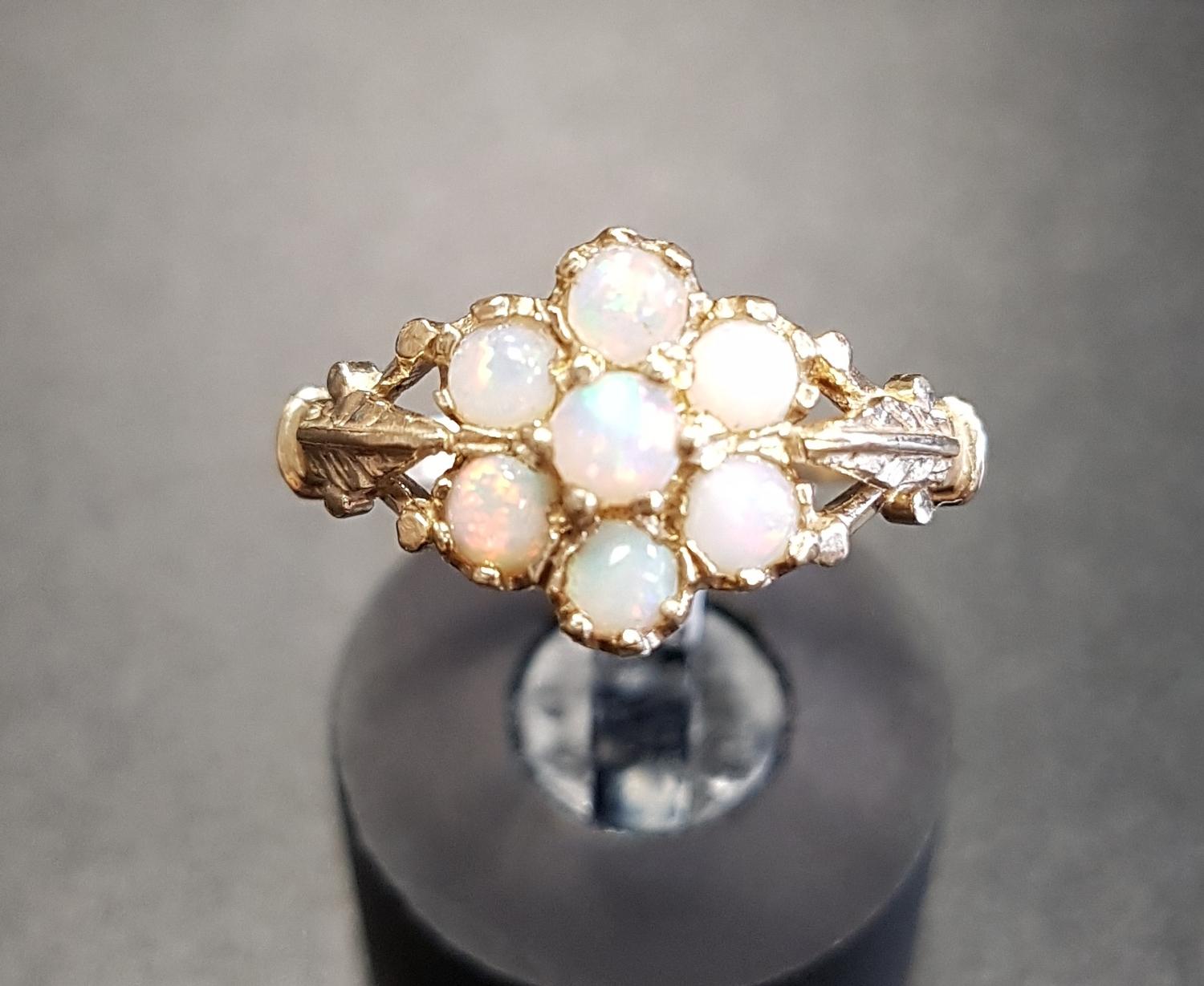 OPAL CLUSTER RING the round cabochon opals flanked by motif decorated shoulders, on nine carat