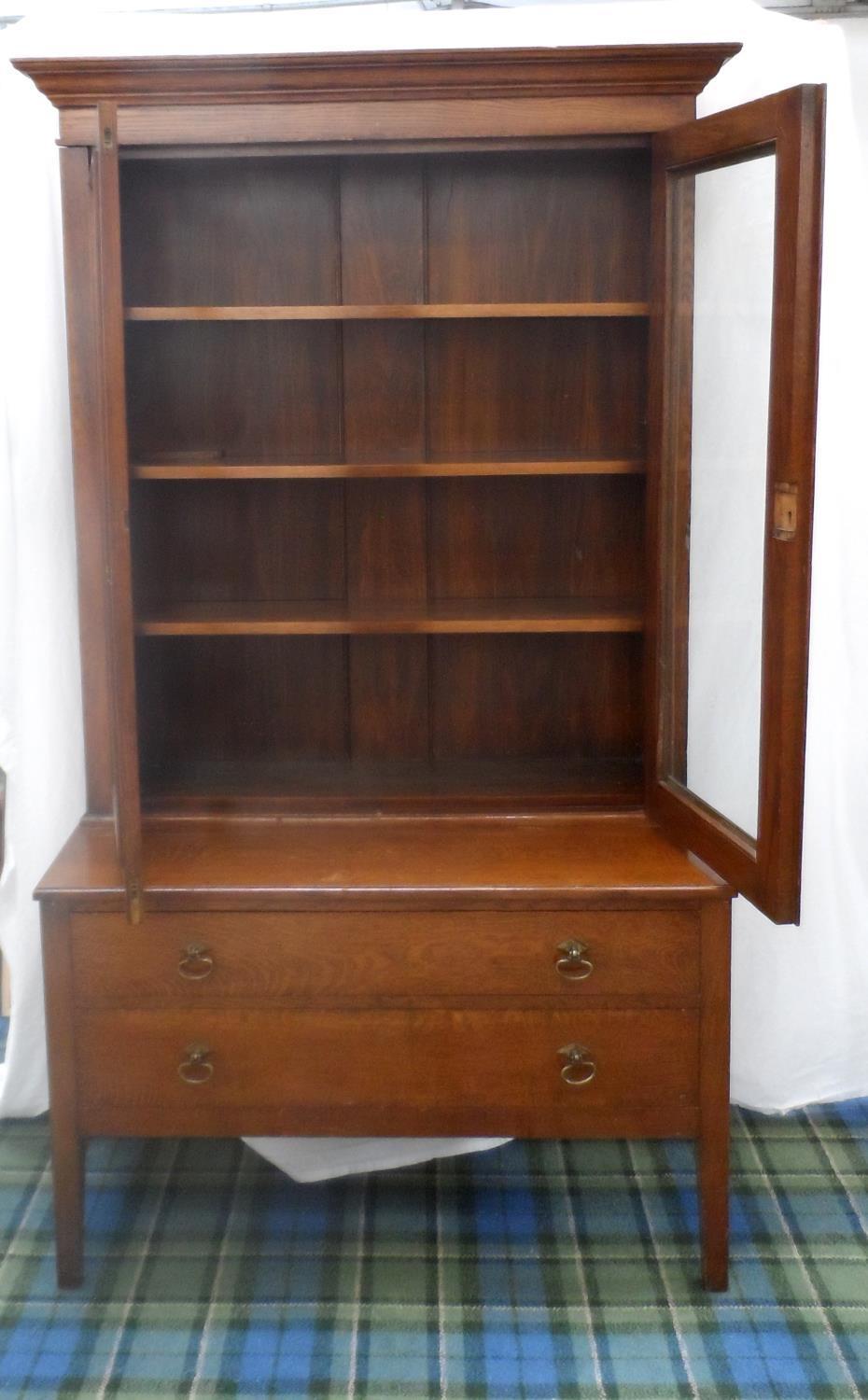 OAK BOOKCASE ON CHEST with a moulded top above a pair of glazed doors opening to reveal adjustable