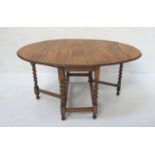 OAK GATE LEG DINING TABLE with shaped drop flaps, standing on barley twist supports united by a