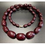 CHERRY AMBER BAKELITE NECKLACE comprising a single strand of graduated beads with a twist clasp,