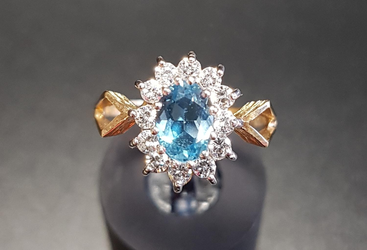 BLUE TOPAZ AND CZ CLUSTER RING the central oval cut topaz in twelve CZ surround, on nine carat