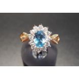 BLUE TOPAZ AND CZ CLUSTER RING the central oval cut topaz in twelve CZ surround, on nine carat