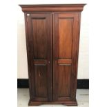 STAINED TEAK WARDROBE with a moulded top above two panelled doors opening to reveal hanging space