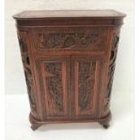 CHINESE CARVED TEAK DRINKS CABINET with profuse carved decoration overall, the shaped lift up lid