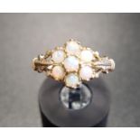 OPAL CLUSTER RING the round cabochon opals flanked by motif decorated shoulders, on nine carat