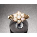 OPAL CLUSTER RING the cluster of seven round cabochon opals flanked by pierced and shaped shoulders,