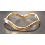 EIGHTEEN CARAT GOLD WAVY BANGLE with safety clasp, approximately 6.3 grams